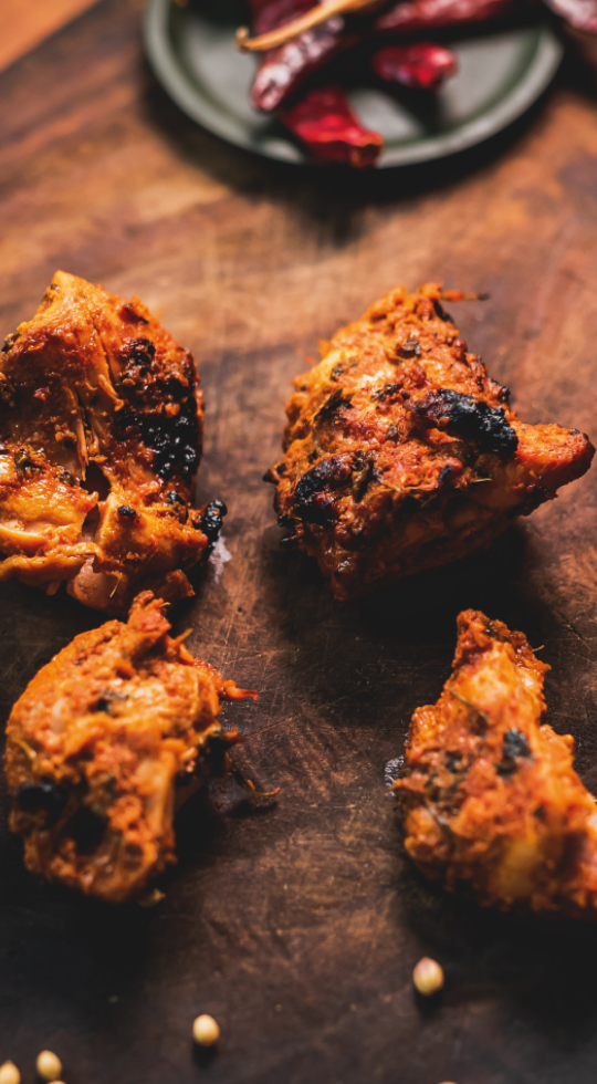Chicken Tikka on a wooden board garnished with chilli